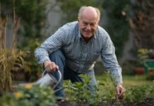 Why Small Sources of Meaning Often Matter More After 50 Senior man gardening in backyard, watering plants, healthy outdoor activity.